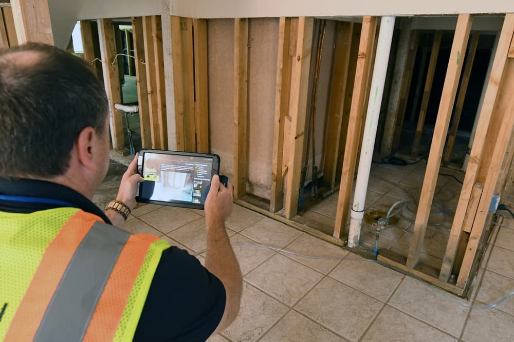 Property inspector documenting exposed interior conditions during a field assessment.
