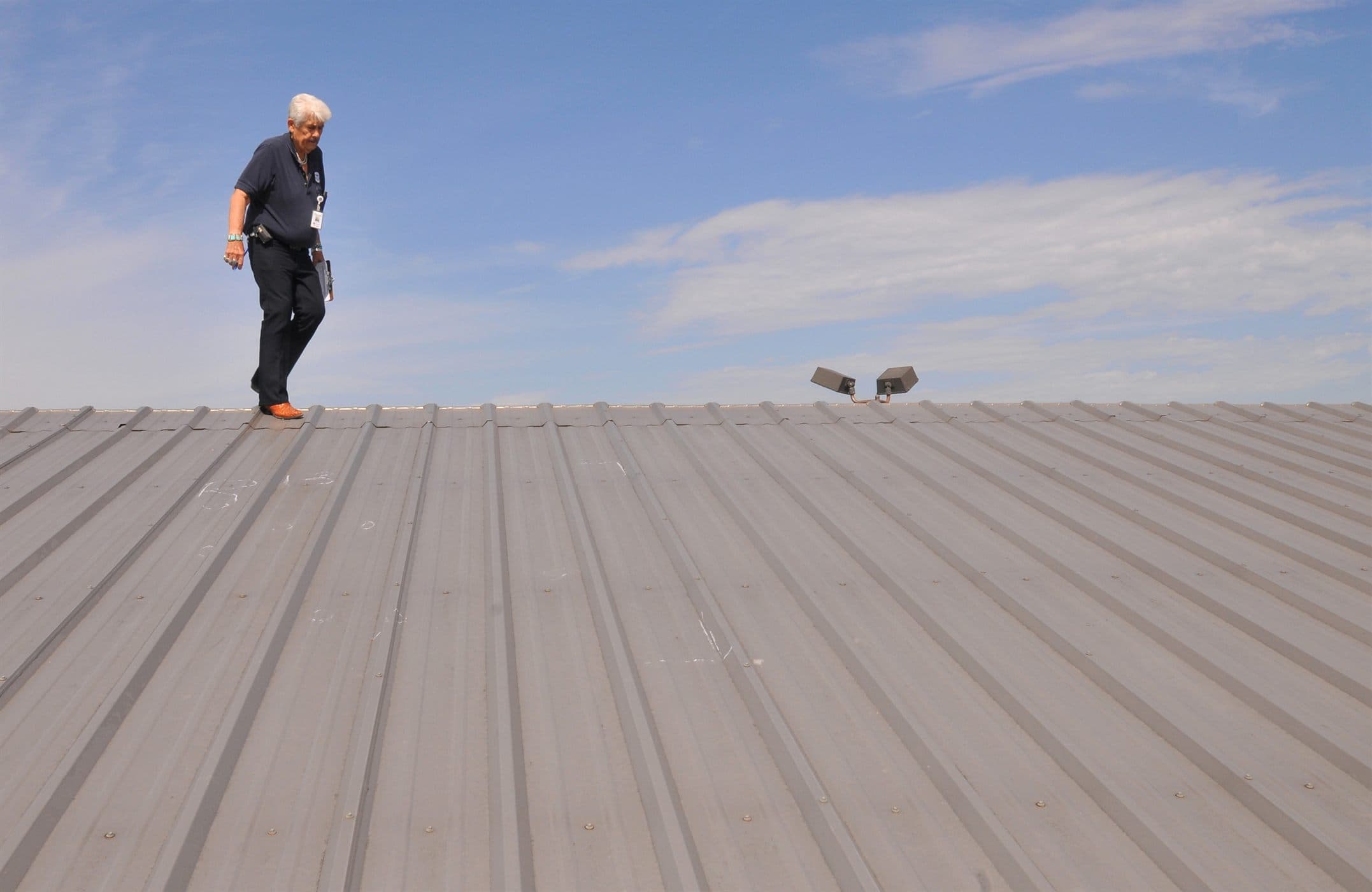 Property inspection professional walking a commercial roof while documenting visible conditions.